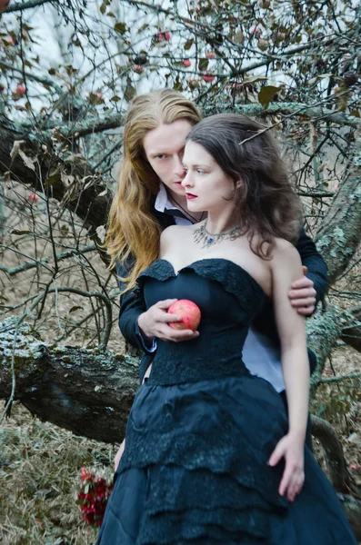 金发碧眼的年轻人拥抱一个深色头发的女孩在一个老花园的飞苹果树下 — 图库照片