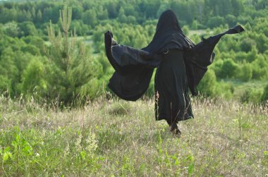 Siyah pelerin kadın cadı çim kaplı bir dağ ormandan chesshouse