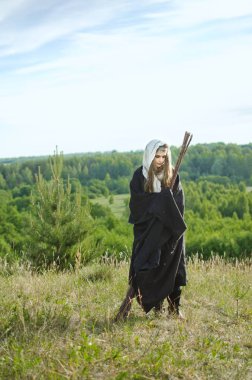 Siyah pelerin ve elbise genç cadı bir Sabbath üzerinde bir dağın tepesinde bir büyülü süpürge ile standları