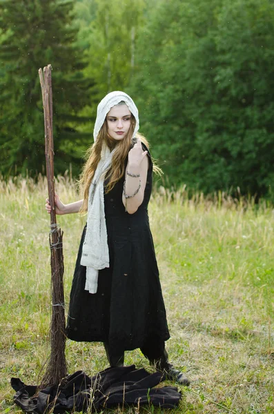 黑色礼服的年轻巫婆和一个扫帚的白色手帕 — 图库照片