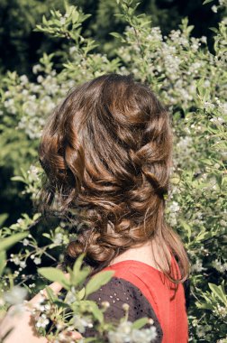 boho tarzı genç kadın onu geri ile kameranın arka planda bir çiçek açan bahar Bush anlamına gelir ve saçını gösterir