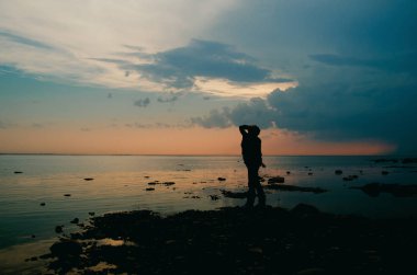 geç gün batımına karşı sahilde bir kadınla-alacakaranlıkta silüeti