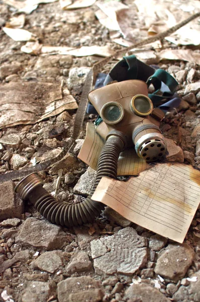 gas mask lies next to a sheet of old burnt paper