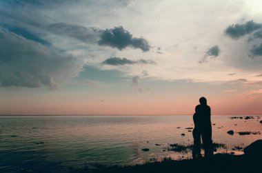 Alacakaranlıkta çift sahilde su üzerinde gün batımını izlemek