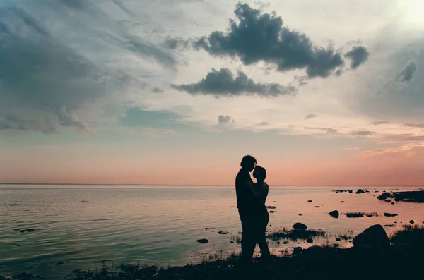 情侣在黄昏在海滩上看日落在水面上 — 图库照片