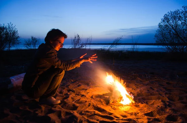 年轻女子游客温暖的手在夜间篝火在海滩上 — 图库照片
