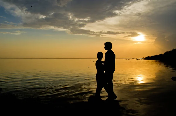 夕日の光の中でビーチにいる人々 のカップルは 穏やかな水について — ストック写真