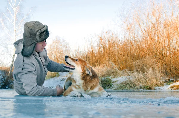 Genç adam bir yürüyüş bir köpek-yalan-buz üzerinde ve köpeği kafasına okşayarak