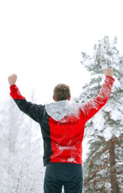 Turistik bir kırmızı kazaklı manzaranın ve ellerini gökyüzüne yükselterek kış orman duruyor