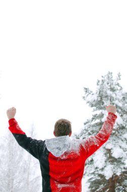 Turistik bir kırmızı kazaklı manzaranın ve ellerini gökyüzüne yükselterek kış orman duruyor