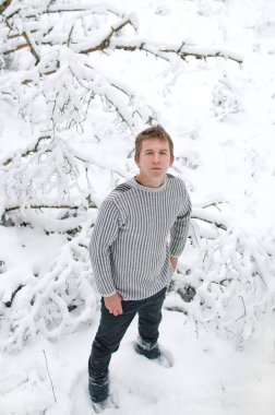 Genç adam kış ormandaki bir yolda