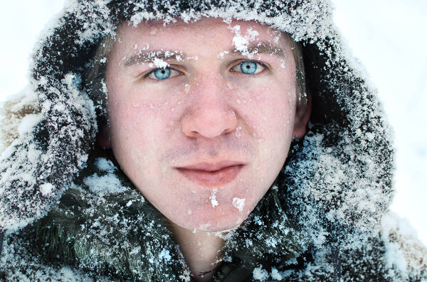 portrait of a blue-eyed Northern man in snow-covered clothes