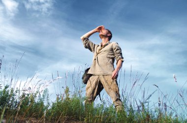 İkinci Dünya Savaşı tam alanında büyüme için bulutlu mavi gökyüzü karşı'eski askeri Üniformalı adam