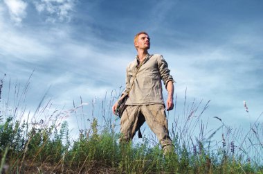 İkinci Dünya Savaşı tam alanında büyüme için bulutlu mavi gökyüzü karşı'eski askeri Üniformalı adam