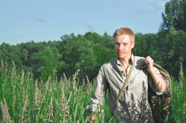 Üniformalı erkeklere bir eski Dünya Savaşı uzun vahşi otlar arasında bir alanda onun elinde büyük bir çanta ile