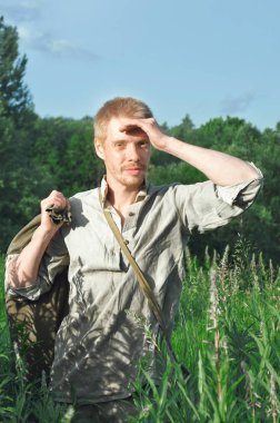 Üniformalı erkeklere bir eski Dünya Savaşı uzun vahşi otlar arasında bir alanda onun elinde büyük bir çanta ile