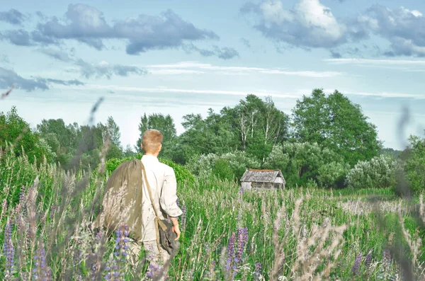 一个穿着旧世界大战的人 在田野里 手里拿着一个大包 在高大的野草中 — 图库照片