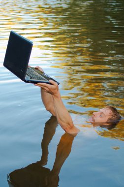 Adam gölde boğuluyor ama laptopunu kurtarmaya çalışıyor. Muhtemelen bir bilgisayar bağımlılığı.