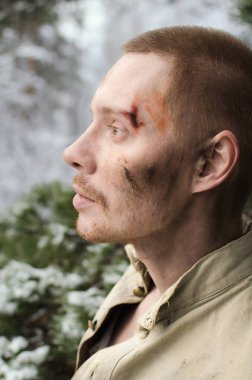 Hırpalanmış yüzlü, askeri üniformalı bir gencin portresi.