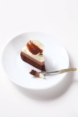 Dilim üç çikolata mousse Cake çikolata Petal ile süslenmiş, beyaz plaka üzerinde, beyaz arka planda.