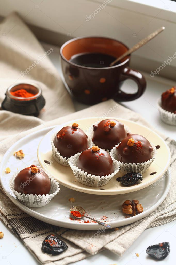 Chocolate Cake Pops with Prunes, Walnuts and Smoked Paprika, served in paper cups on plate, on light background.