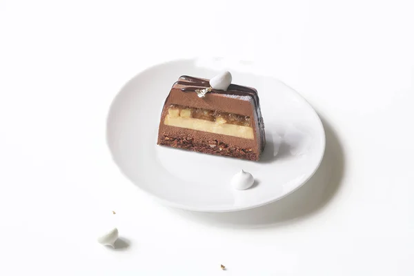 Contemporary Apple Chocolate Mousse Cake covered with white velvet spray and cocoa glaze, on white background.