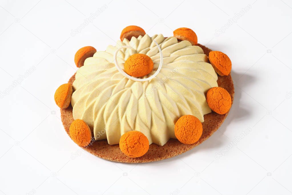 Contemporary version of the famous french Saint Honore Cake, decorated with choux buns with craquelin - (crispy cream puffs), covered with yellow velvet spray, on white background. 