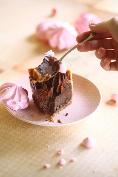 Chocolate Truffle Cake on a Graham Cracker Crust, decorated with pink meringue cookies, on a light background.