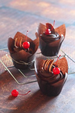 Kahverengi kağıt bardak Çikolata Cherry Cupcakes, koyu kahverengi arka plan üzerinde.