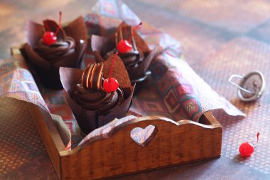 Kahverengi kağıt bardak Çikolata Cherry Cupcakes, koyu kahverengi arka plan üzerinde.