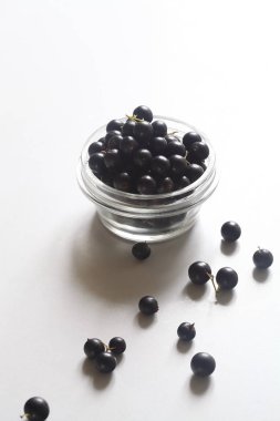 Şeffaf cam tencerede siyah frenk üzümü, beyaz arka plan üzerinde.