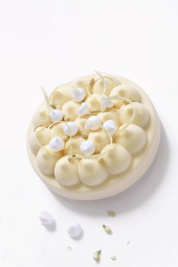 Çağdaş Yasemin Çayı, Kiraz ve Lychee Mus Kek, kadife sprey kaplama ile kaplı, beze çerezleri ile dekore edilmiş, kurutulmuş yasemin tomurcukları ve beyaz çikolata elemanları, beyaz arka plan üzerinde.