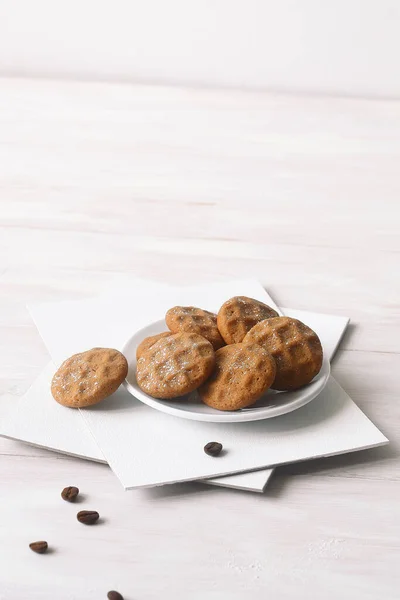 Coffee Butter Cookies, powdered with icing sugar, on a white wooden table.