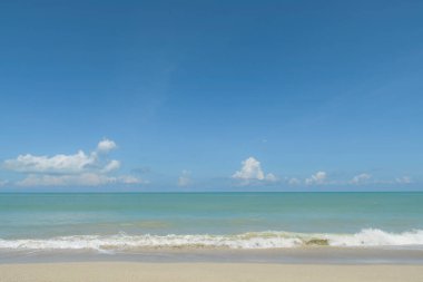 Mavi gökyüzünün, zümrüt okyanusun ve parlak gün ışığında kumsalın arka planında rahatla..