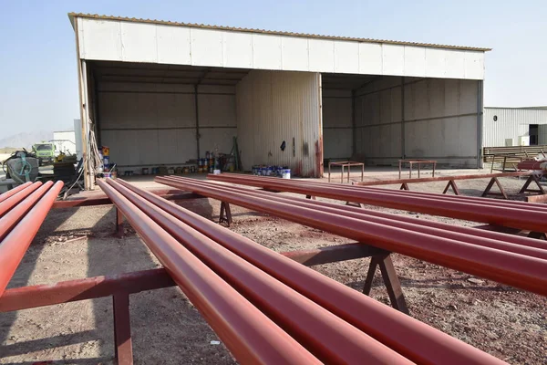 Red steel pipes for fire fighting system and extinguishing water lines in industrial building. Paint shop. Steel pipe painted red color for installation the fire protection system.