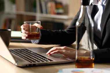 Close up of entrepreneur woman hands drinking alcohol working on laptop sitting on a desk at homeoffice clipart