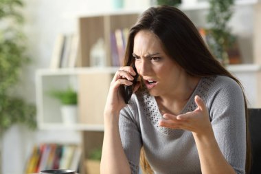 Kızgın kadın arayıp akıllı telefondan tartışıyor. Oturma odasında oturuyor.