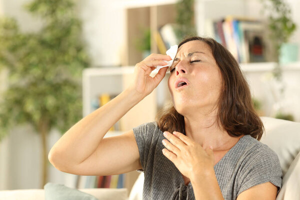 Adult woman sweating suffering heat stroke sitting in the coach at home