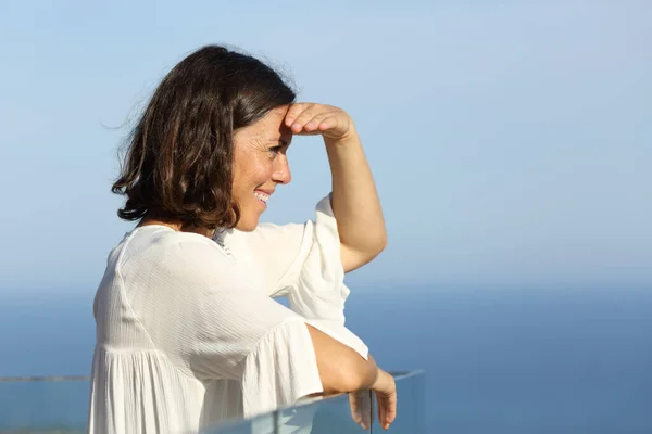 一位快乐的成年女子站在海滩上的阳台上观看风景时的侧景肖像画 — 图库照片