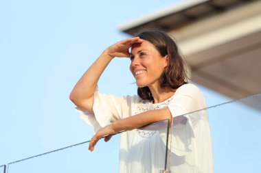 Yaz tatilinde otel balkonunda bekleyen mutlu yetişkin kadın.