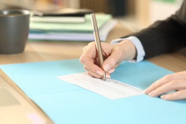 Girişimci kadınların elleri banka çekini doldururken yakınlarda bir ofis masasında oturuyorlar.