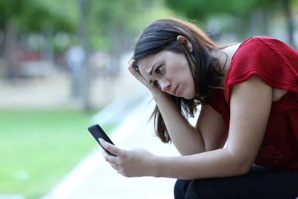 Trieste Vrouw Zit Een Bank Een Park Controleren Smart Phone — Stockfoto