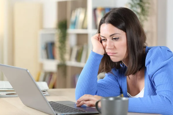 Скучная Женщина Проверяет Ноутбук Онлайн Контент Сидя Столе Дома — стоковое фото