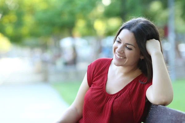 快乐的女人放松地坐在公园的长椅上 — 图库照片