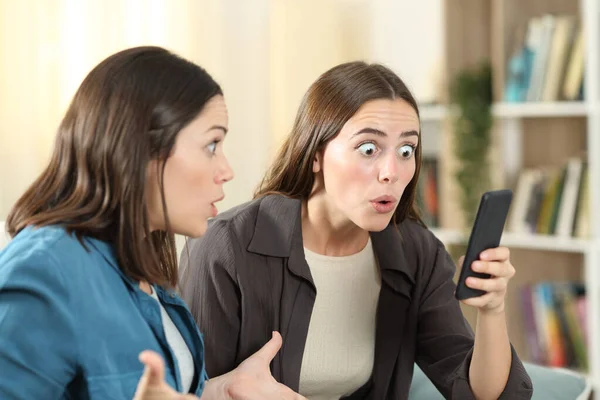 Two Surprised Friends Checking Smart Phone Content Couch Living Room — Stock Photo, Image