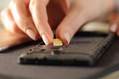 Sim kartı akıllı telefona yerleştiren kadınların yakınlaşması.