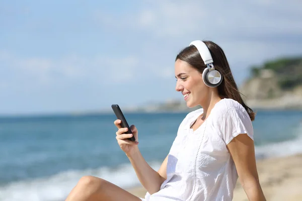 Cep Telefonuyla Müzik Dinleyen Mutlu Bir Genç Kumsalda Kumsalda Oturuyor — Stok fotoğraf