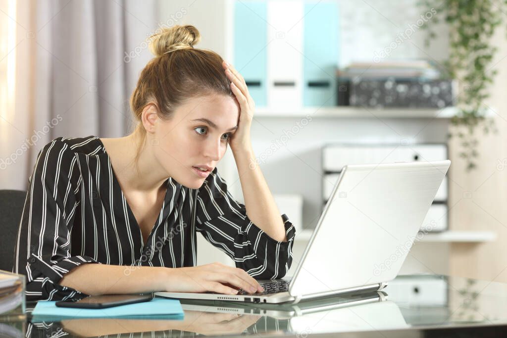 Worried businesswoman discovering online mistake on laptop on a desk at office