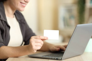 Elinde boş bir kredi kartı olan bir kadının evinde bilgisayarla çevrimiçi ödeme yapmasını kapat.