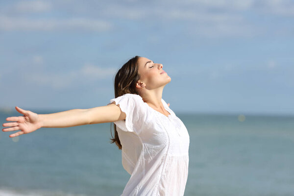 Расслабленная женщина на белых вытянутых руках дышит свежим воздухом на пляже
